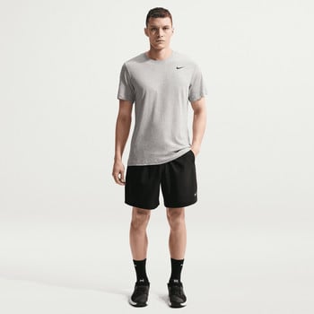 Ein Mann in einem grauen Nike-T-Shirt und schwarzer Hose steht in einer Pose.