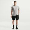 Ein Mann in einem grauen Nike-T-Shirt und schwarzer Hose steht in einer Pose.