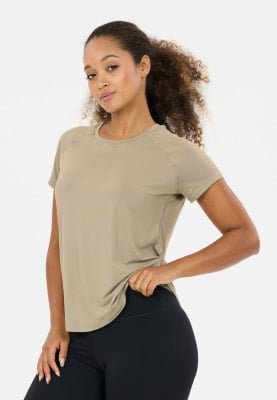 Eine Frau in einem beigefarbenen Shirt und schwarzer Leggings posiert vor weißem Hintergrund. Eine Frau in einem beigefarbenen Shirt und schwarzer Leggings posiert vor weißem Hintergrund.