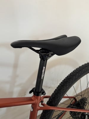 Schwarze Sattelstütze mit Ergotec-Logo auf einem orangefarbenen Fahrradrahmen. Schwarze Sattelstütze mit Ergotec-Logo auf einem orangefarbenen Fahrradrahmen.