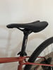 Schwarze Sattelstütze mit Ergotec-Logo auf einem orangefarbenen Fahrradrahmen.