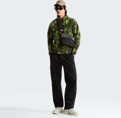 Ein Mann im Camouflage-Fleecepullover und schwarzer Cargohose mit Bauchtasche. Ein Mann im Camouflage-Fleecepullover und schwarzer Cargohose mit Bauchtasche.