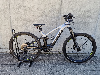 Silbernes Genesis E-Bike auf einem Ständer vor einer Betonwand.