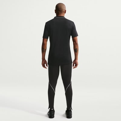 Ein Mann in einem schwarzen Poloshirt und Hose mit weißer Paspel steht mit dem Rücken zur Kamera. Ein Mann in einem schwarzen Poloshirt und Hose mit weißer Paspel steht mit dem Rücken zur Kamera.