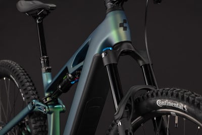Detail eines Mountainbike-E-Bikes mit Federung und Dämpfer vor dunklem Hintergrund.