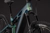 Detail eines Mountainbike-E-Bikes mit Federung und Dämpfer vor dunklem Hintergrund.