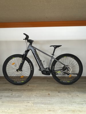 Ein graues Genesis E-Bike steht auf einem Holzboden vor einer weißen Wand. Ein graues Genesis E-Bike steht auf einem Holzboden vor einer weißen Wand.
