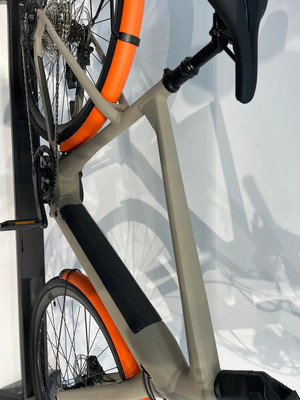 Nahaufnahme des E-Bike-Rahmens mit orangen Schutzblechen und Sattel.