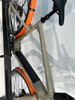Nahaufnahme des E-Bike-Rahmens mit orangen Schutzblechen und Sattel.