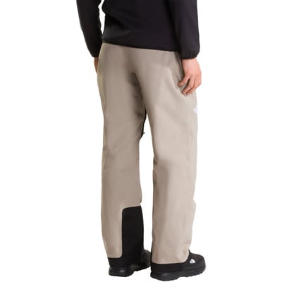 Ein Mann in beigen Hosen mit schwarzen Details und einem Logo am Bein. Ein Mann in beigen Hosen mit schwarzen Details und einem Logo am Bein.