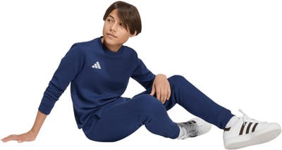 Ein Junge im dunkelblauen Adidas-Anzug sitzt auf dem Boden. Ein Junge im dunkelblauen Adidas-Anzug sitzt auf dem Boden.