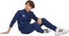 Ein Junge im dunkelblauen Adidas-Anzug sitzt auf dem Boden.