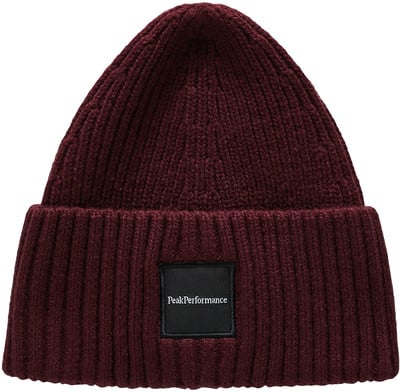 Eine weinrote Strickmütze mit schwarzem PeakPerformance-Aufnäher.