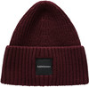 Eine weinrote Strickmütze mit schwarzem PeakPerformance-Aufnäher.