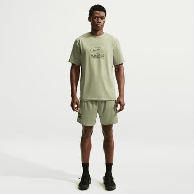 Ein Mann in einem grünen Nike-T-Shirt und Shorts mit Logo auf weißem Hintergrund.