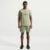 Ein Mann in einem grünen Nike-T-Shirt und Shorts mit Logo auf weißem Hintergrund.
