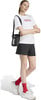 Model in weißem T-Shirt, schwarzer Hose und roten Socken mit Tasche.