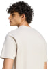 Mann mit lockigem Haar in einem beigen T-Shirt im Profil.