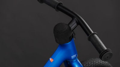 Detail eines blauen Kinderfahrrads mit schwarzem Lenker und Schaumstoffabdeckung. Detail eines blauen Kinderfahrrads mit schwarzem Lenker und Schaumstoffabdeckung.