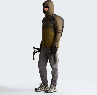 Ein Mann in Outdoor-Kleidung mit Rucksack, Wanderstöcken und Wasserflasche.