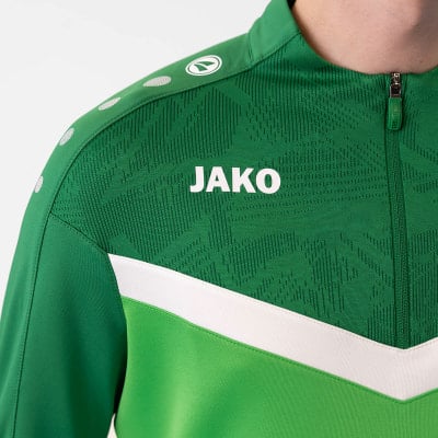 Detail einer JAKO Jacke mit Reißverschluss und Logo auf grünem Hintergrund. Detail einer JAKO Jacke mit Reißverschluss und Logo auf grünem Hintergrund.