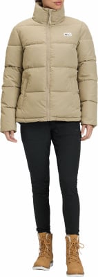 Damen-Daunenjacke in Beige mit hohem Kragen und schwarzer Hose. Damen-Daunenjacke in Beige mit hohem Kragen und schwarzer Hose.