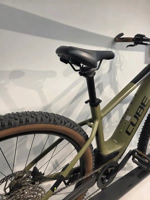 Grünes Mountain-E-Bike mit schwarzem Sattel und braunen Reifen.
