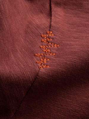 Stoffdetail mit oranger Nahtverzierung. Stoffdetail mit oranger Nahtverzierung.