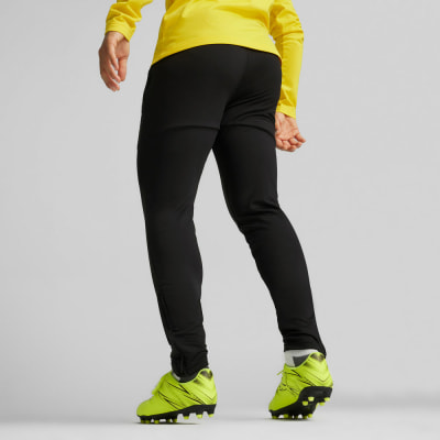 Rückansicht einer Person in schwarzer Hose und gelbem Oberteil mit Fußballschuhen. Rückansicht einer Person in schwarzer Hose und gelbem Oberteil mit Fußballschuhen.