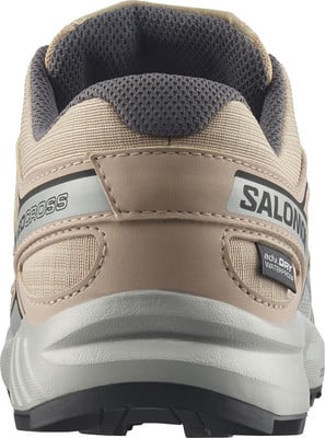 Detail der Rückseite eines beigen Salomon Laufschuhs mit Logo und Schriftzug. Detail der Rückseite eines beigen Salomon Laufschuhs mit Logo und Schriftzug.