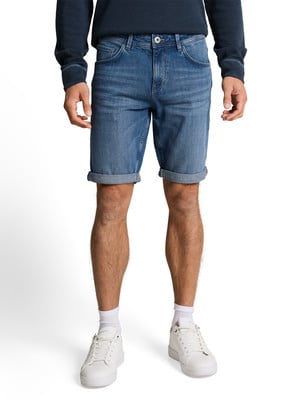 Férfi kék farmer sortban és fehér sportcipőben fehér háttérrel.