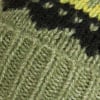 Detail eines Strickmusters in Grün- und Schwarztönen mit unregelmäßigen hellen Punkten.