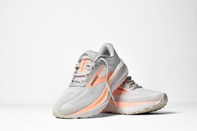Graue Brooks Laufschuhe mit orangefarbenen Details auf weißem Hintergrund. Graue Brooks Laufschuhe mit orangefarbenen Details auf weißem Hintergrund.
