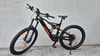 Ein schwarzes KTM E-Mountainbike mit orangefarbenen Akzenten steht an einer Wand.