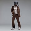 Skifahrerin in brauner Jacke, Hose, Helm und Skibrille.
