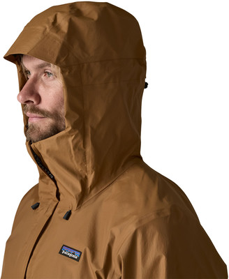 Mann in brauner Jacke mit Kapuze und Patagonia-Logo auf der Brust. Mann in brauner Jacke mit Kapuze und Patagonia-Logo auf der Brust.