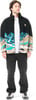 Ein Mann in schwarzer Hose und einer Fleecejacke mit Bergmotiv.