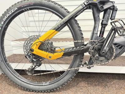 Hinterer Teil eines gelben E-Mountainbikes mit Dämpfer und Kette.