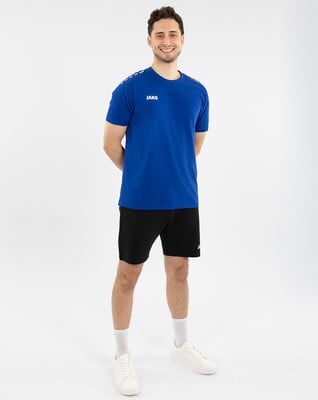 Ein junger Mann in einem blauen T-Shirt und schwarzen Shorts steht mit verschränkten Händen. Ein junger Mann in einem blauen T-Shirt und schwarzen Shorts steht mit verschränkten Händen.