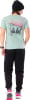 Mann in mintgrünem T-Shirt mit Berg- und Skifahrerdruck, schwarzer Jogginghose und Turnschuhen.