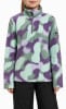 Mädchen in einem bunten Fleece-Pullover mit Tarnmuster und schwarzer Hose.