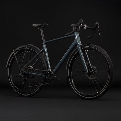 Graues Gravelbike mit Schutzblechen und Gepäckträger vor schwarzem Hintergrund. Graues Gravelbike mit Schutzblechen und Gepäckträger vor schwarzem Hintergrund.