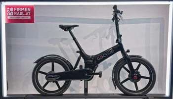 Ein schwarzes GoCycle-Elektrofahrrad steht mit einem Schild links ausgestellt.