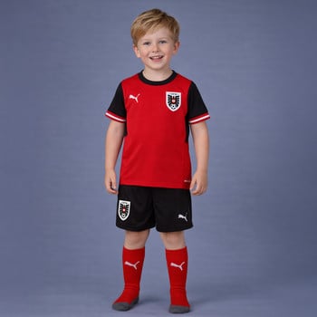Junge in einem roten Fußballtrikot von Österreich mit schwarzen Ärmeln und Shorts.
