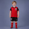 Junge in einem roten Fußballtrikot von Österreich mit schwarzen Ärmeln und Shorts.