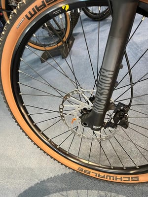 Nahaufnahme eines Mountainbikes mit braunem Reifen und RockShox-Federgabel. Nahaufnahme eines Mountainbikes mit braunem Reifen und RockShox-Federgabel.