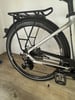 Rückseite eines silbernen Fahrrads mit Gepäckträger, Schaltwerk und Pedal.