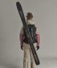 Frau in Skibekleidung mit Skiern auf dem Rücken