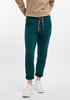 Dunkelgrüne Damenhose mit grauem Kordelzug und weißen Sneakern.