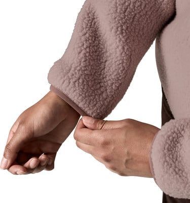 Hände passen den Saum eines rosa Plüschpullover-Ärmels an. Hände passen den Saum eines rosa Plüschpullover-Ärmels an.